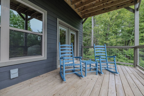 The covered deck offers a quiet place for morning coffee, evening drinks, and wooded mountain views.