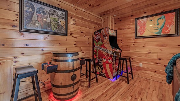 Um interior de madeira com um jukebox, um barril e obras de arte emolduradas nas paredes.