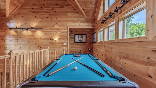 A pool table with pool cues and a cue ball, wooden walls, and a window with a view. - Near Downtown Gburg, Theater, Views, Trailer Parking,Dogs OK! (Gatlinburg)