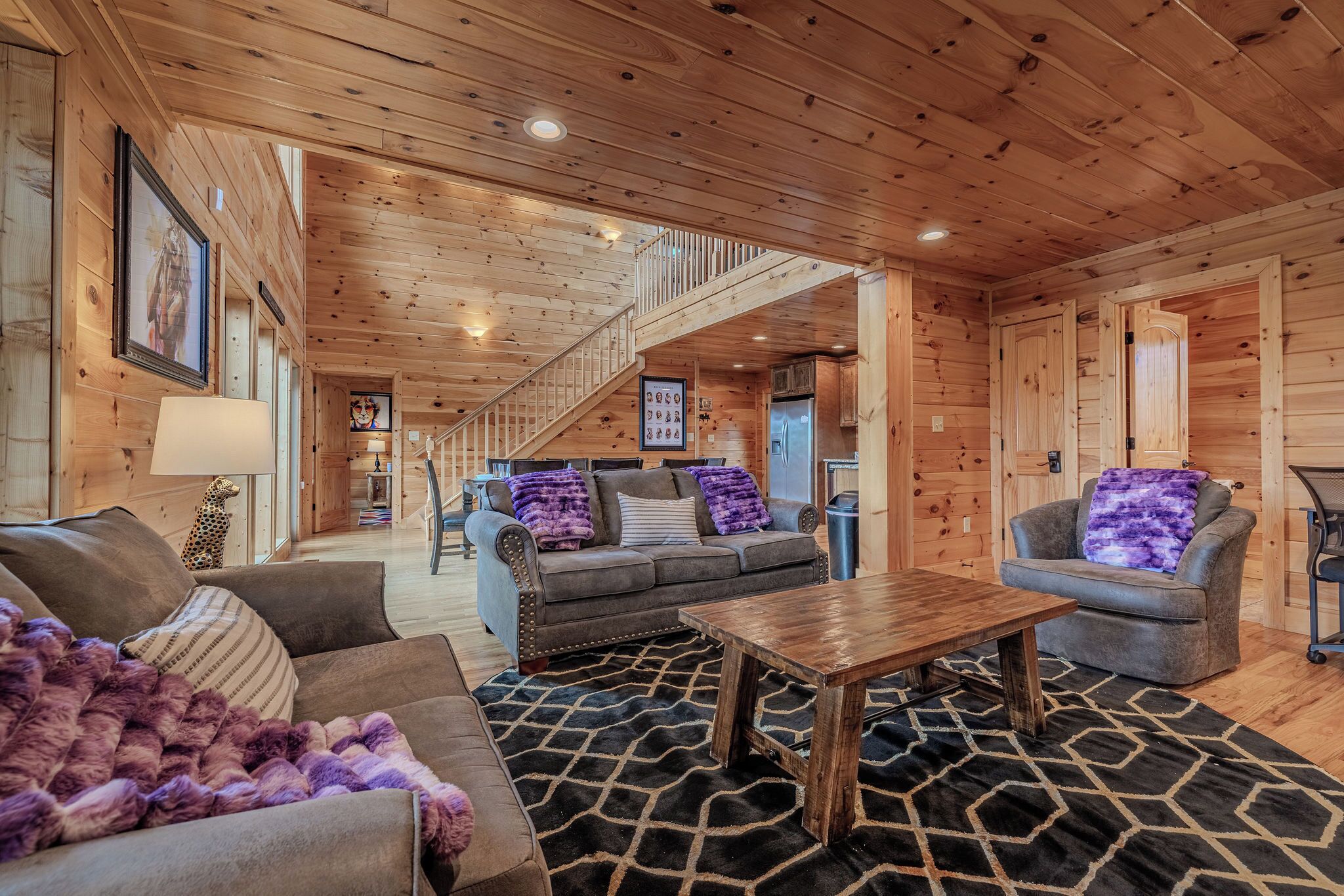 Ein Holzblockhaus-Interieur mit Treppe, Holzwänden, einer Couch, einem Couchtisch und einem gemusterten Teppich.
