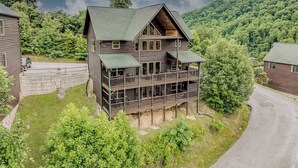 A two-story log cabin with a balcony, surrounded by lush greenery and a mountain backdrop. - Near Downtown Gburg, Theater, Views, Trailer Parking,Dogs OK! (Gatlinburg)