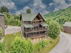 A two-story log cabin with a balcony, surrounded by lush greenery and a mountain backdrop. - Near Downtown Gburg, Theater, Views, Trailer Parking,Dogs OK! (Gatlinburg)