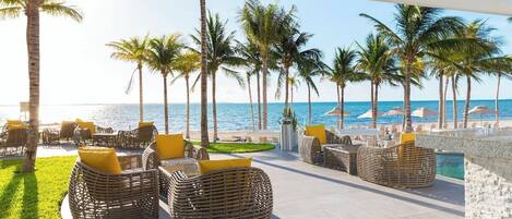 A resort patio with wicker furniture and a view of the ocean.