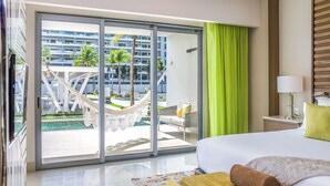 Hotellihuone, jossa on suuri sänky, näkymä uima-allasalueelle ja liukuovet, jotka ovat lasia.