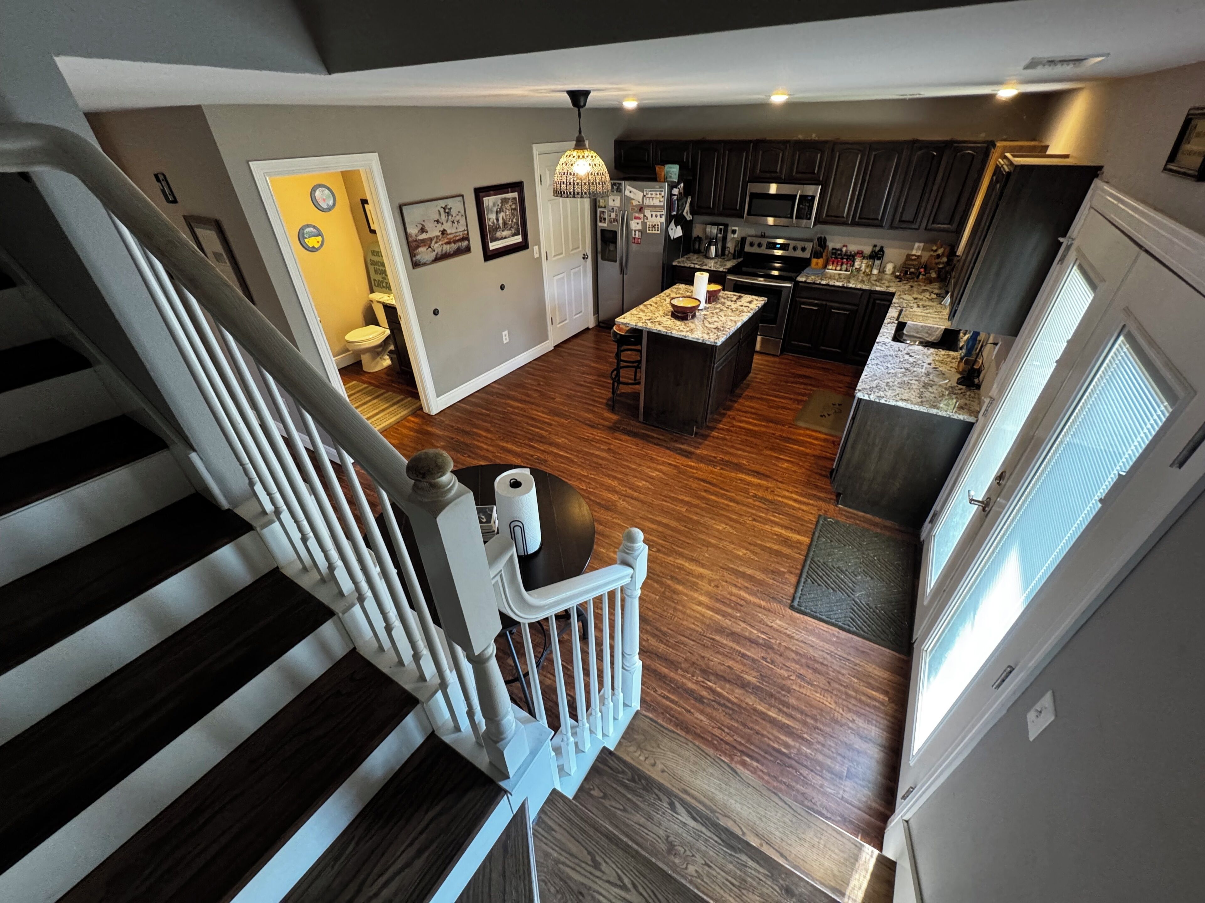 A modern kitchen with dark wood flooring, a central island, and stainless steel appliances.