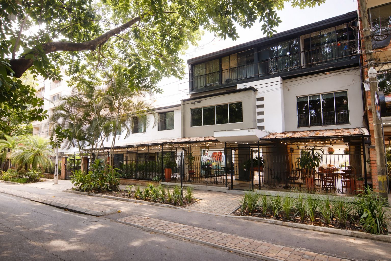 A two-story building with a covered outdoor seating area and a gated entrance.