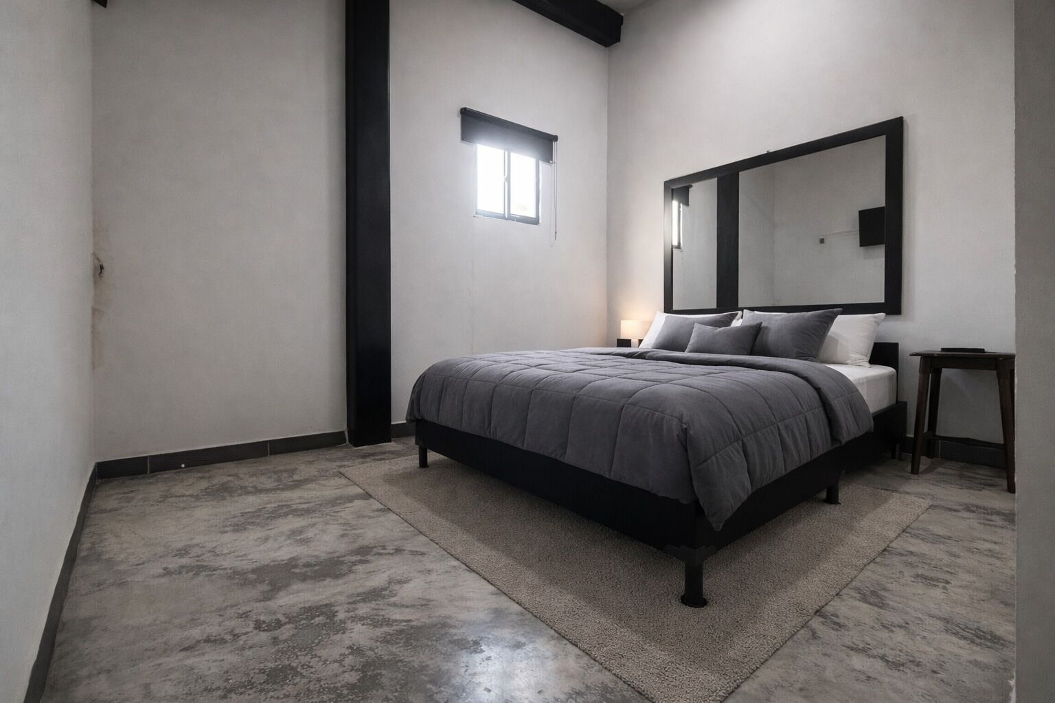 Quarto com cama, mesa de cabeceira, espelho e uma pequena janela.