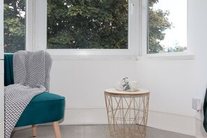 A room with a teal chair, a small round table with a white top, and a window with a view of trees. - En-Suite Room near University of Aberdeen (Aberdeen)