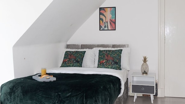 Une chambre à coucher avec un lit, une table de chevet, un tableau encadré et un ananas posé sur la table de chevet.