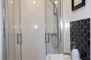 A bathroom with a glass-enclosed shower, a white sink, and a black and white mosaic tile backsplash. - En-Suite Room near University of Aberdeen (Aberdeen)
