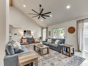 A spacious living room with a modern ceiling fan, a sofa set, a coffee table, and a rug.