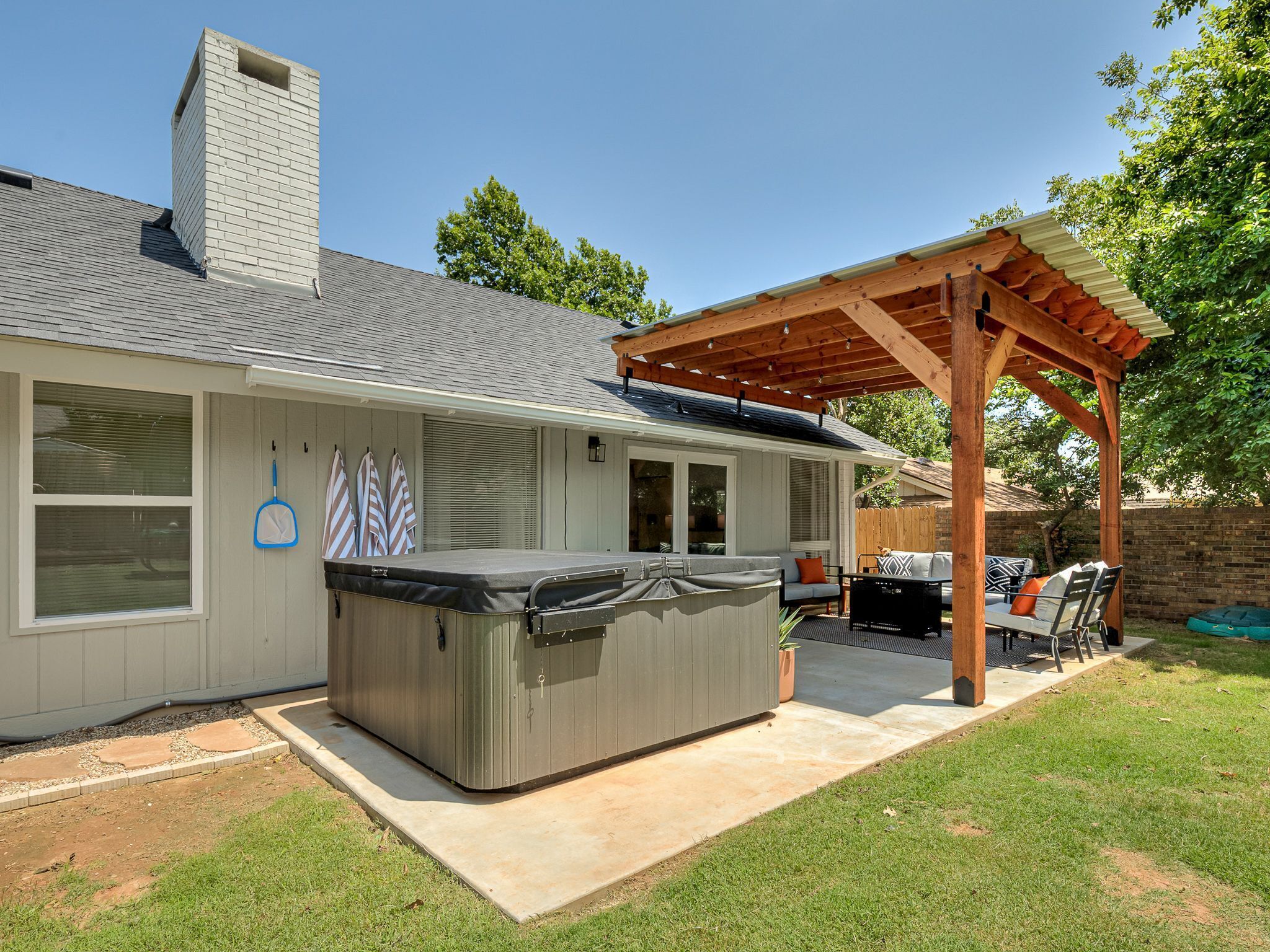 A house with a covered patio, a hot tub, and outdoor furniture.