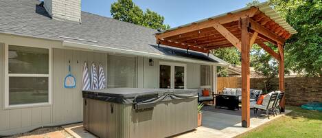 A house with a covered patio, a hot tub, and outdoor furniture.
