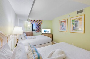 Ein Hotelzimmer mit zwei Betten, einem Fernseher, einer Lampe und Bildern an der Wand.