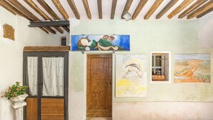 Una habitación rústica con una puerta de madera, una ventana con cortinas y un cuadro en la pared.