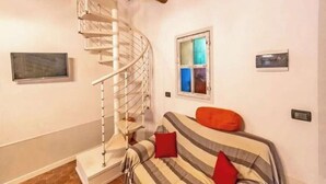 Una habitación con una escalera en espiral, una cama con ropa de cama a rayas y un ventanal.