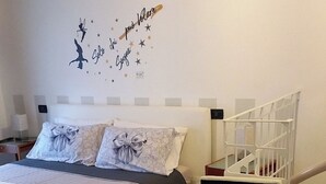Un dormitorio con una cama, un adhesivo decorativo en la pared, un aparador blanco y un techo de madera.