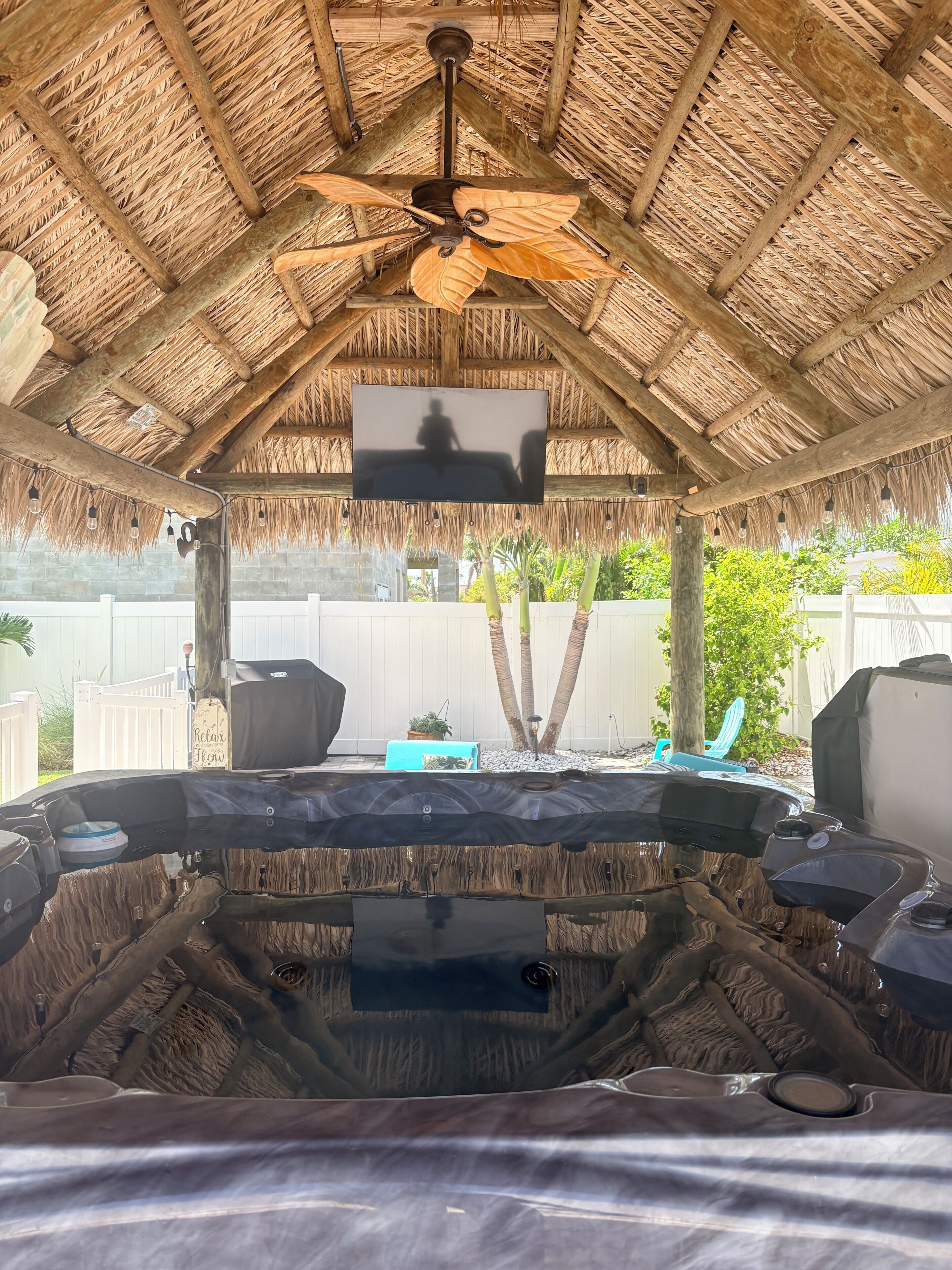 Un jacuzzi con techo de paja y ventilador de techo.