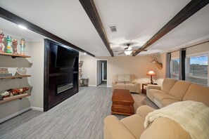 A living room with a flat-screen TV, a sofa, a coffee table, and a fireplace. - Peaceful 4BR County Home on 12 Acres with Barn and Shop, (Teague)