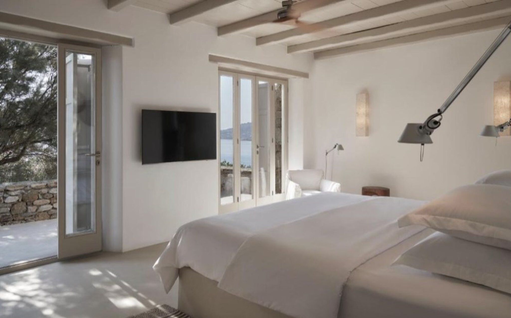 Quarto com cama, televisão e vista para o exterior.