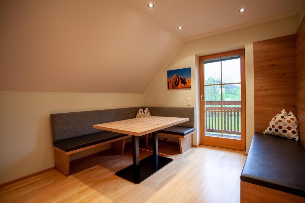A cozy room with a wooden bench, a table, and a window with a view of greenery.