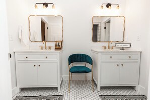 Ein Badezimmer mit zwei Waschbecken, einem Spiegel und einem Stuhl.