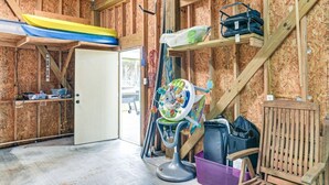 Um quarto com interior em madeira, uma porta branca, um espaço de brincadeiras infantil colorido e um caiaque no teto.