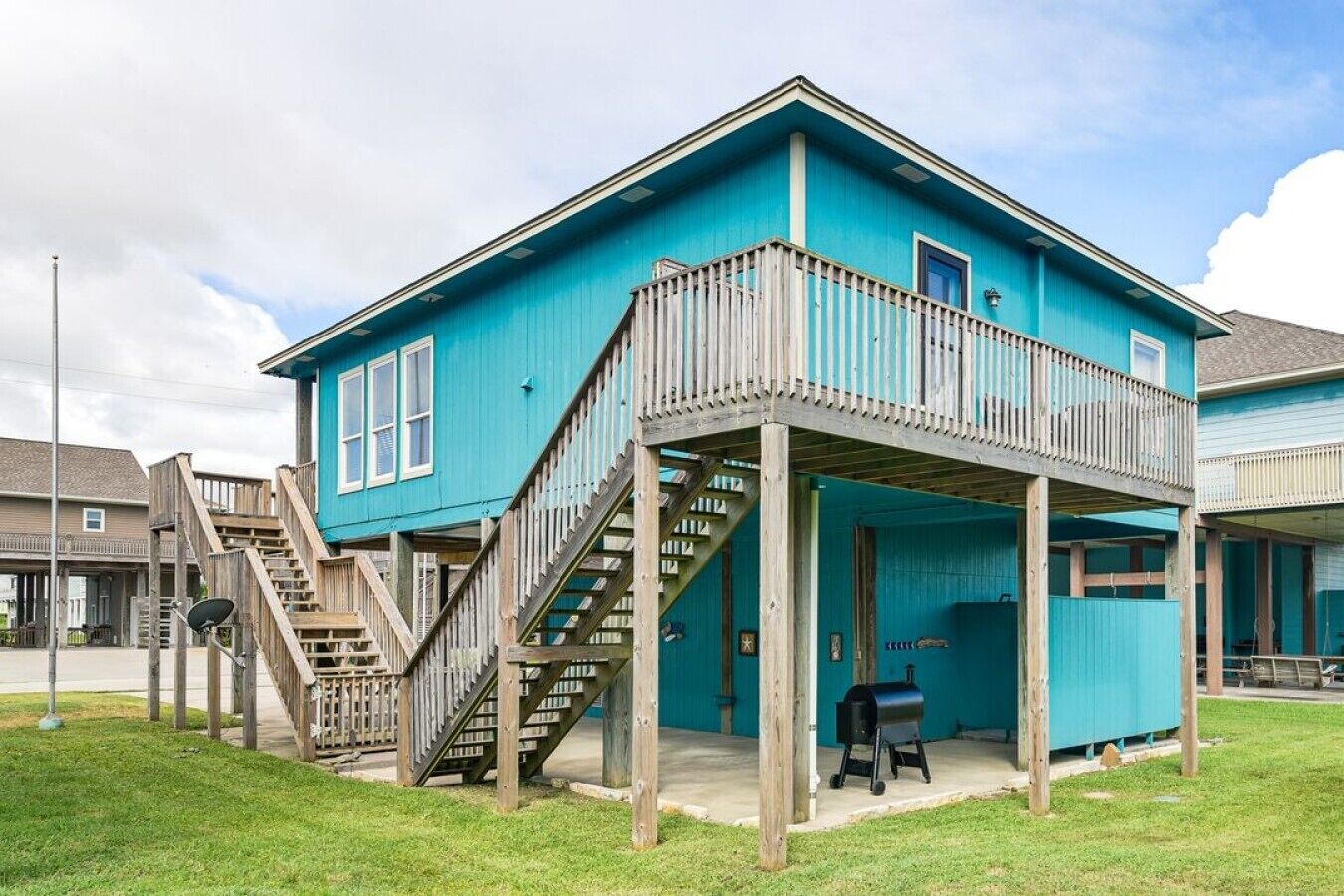 Un bâtiment à deux étages doté d’un balcon, d’un escalier et d’un barbecue à l’extérieur.