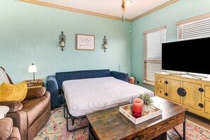 A cozy room with a bed, a sofa, a television, and a wooden cabinet. - Walk to Crystal Beach - Family Retreat (Bolivar Peninsula)