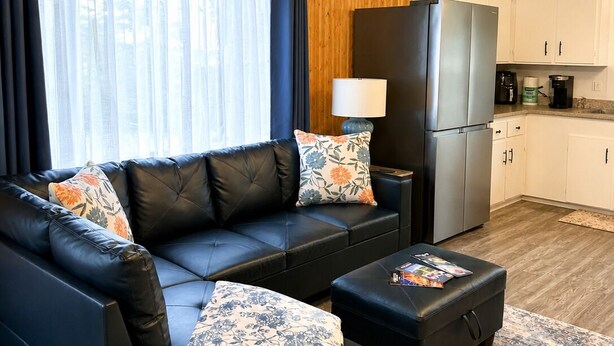 A modern living room with a sofa, ottoman, and a small table with a lamp. - Hydrangeas at Stanley Bridge #4 (Breadalbane)