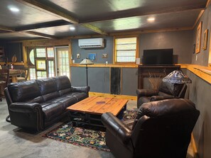 Una sala de estar con sofás de cuero, una mesa de centro de madera y un tapete estampado.