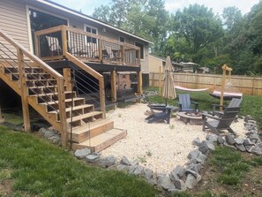 A wooden deck with a staircase leading to a covered area, outdoor seating, and a hammock. - Fireside forest retreat Hammocks & Large deck (Charlotte)