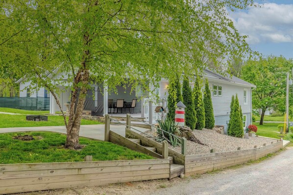 A residential property with a covered porch, a small garden, and a gravel driveway. - Cozy Cottage on Turkey Lake/kayaks/Game room! (LaGrange)