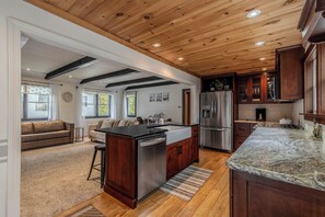 A spacious kitchen with wooden cabinets, a stainless steel refrigerator, and a large island with a sink. - Cozy Cottage on Turkey Lake/kayaks/Game room! (LaGrange)