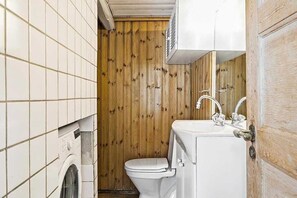 Ein kleines Badezimmer mit Waschmaschine, Toilette und Waschbecken.