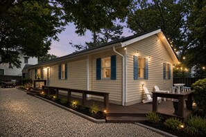 Eingeschossiges Haus mit überdachter Veranda, Sitzgelegenheit im Freien und Lichterketten.