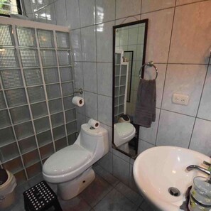 A bathroom with a toilet, sink, and mirror. - The King's Panoramic Ocean View (Unknown)