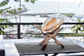 Eine Muscheldekoration auf einem Holzboden, im Hintergrund ein Blick auf einen Yachthafen.