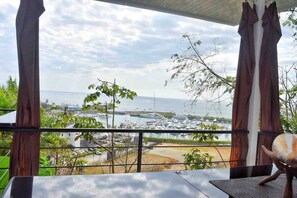 A view from a balcony overlooking a marina with boats, greenery, and a clear sky. - Sunset Lovers - Crazy View (Unknown)