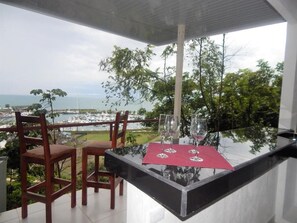 A balcony with a glass table, two chairs, and a red table runner. - Sunset Lovers - Crazy View (Unknown)