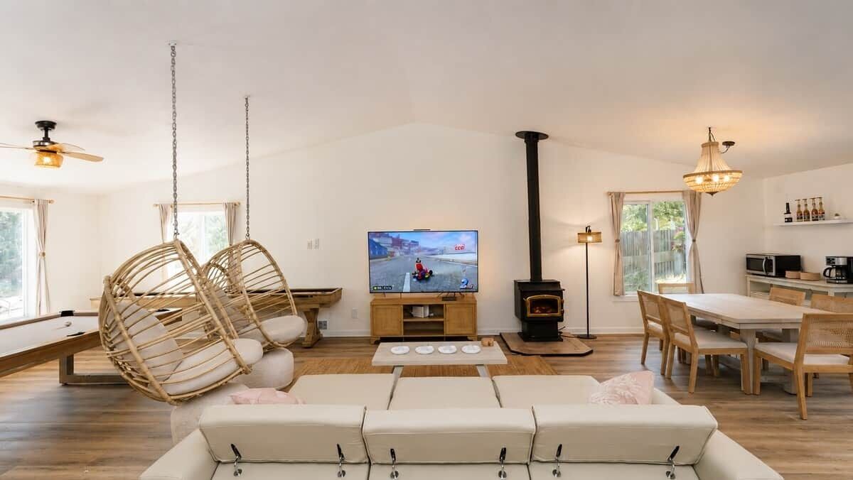 A living room with a television, a fireplace, a dining area, and a hanging chair.