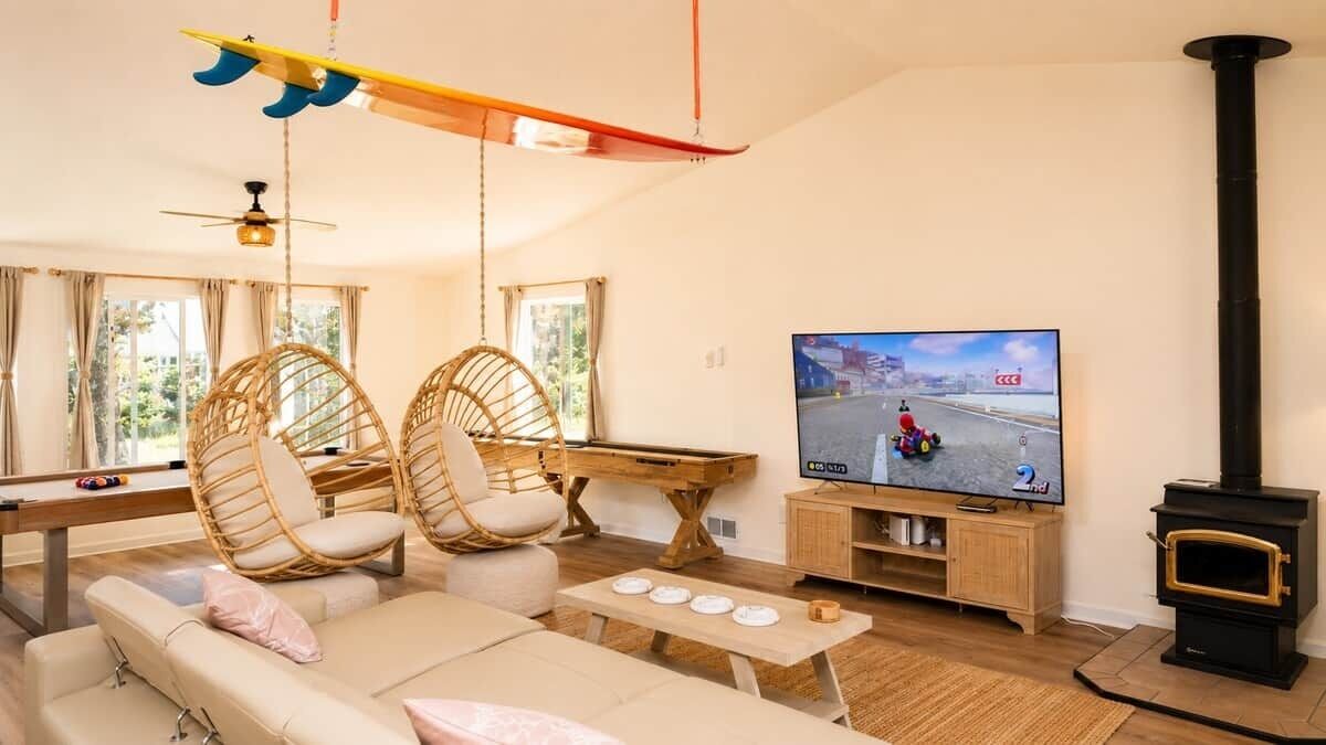 A cozy living room with a sofa, two wicker chairs, a wooden coffee table, a television, and a wood-burning stove.