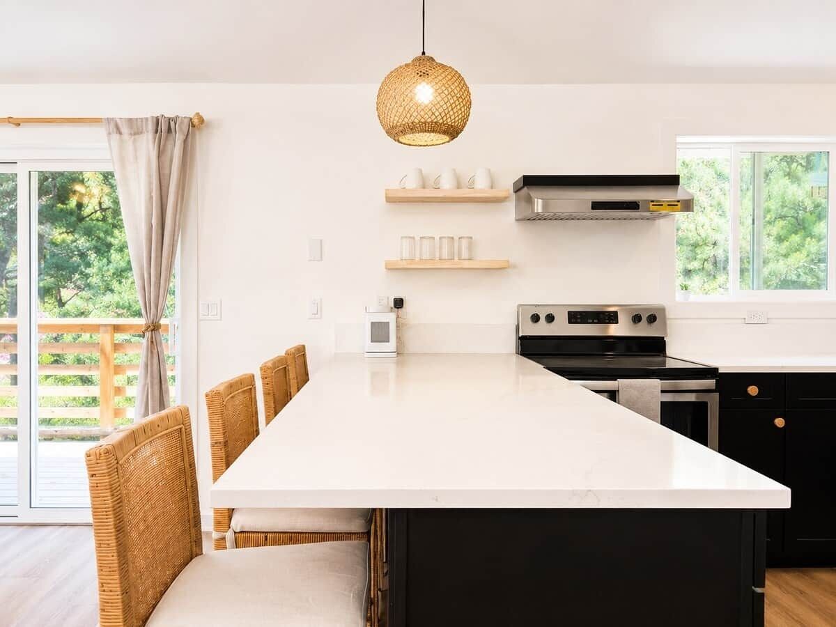 A modern kitchen with a central island, black cabinets, and a hanging light fixture.