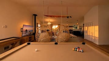 Una mesa de billar con bolas, una mesa de madera y un cuadro en la pared.