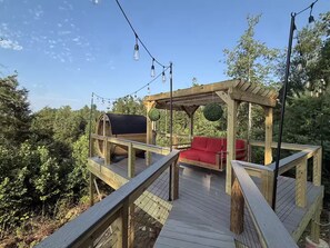 Eine Holzterrasse mit einer Schaukel und einem überdachten Sitzbereich.