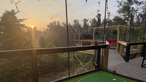 Une terrasse dotée d’un mini-parcours de golf, d’une pergola en bois et offrant une vue sur le coucher de soleil.