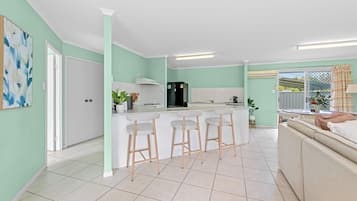 Une cuisine moderne dotée d’un îlot central, de tabourets de bar et d’un coin repas avec un canapé.