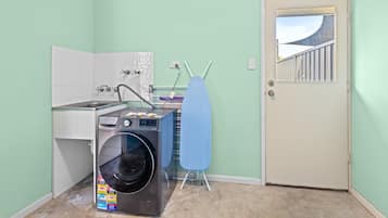 A laundry room with a washing machine, a drying rack, and a door leading outside.