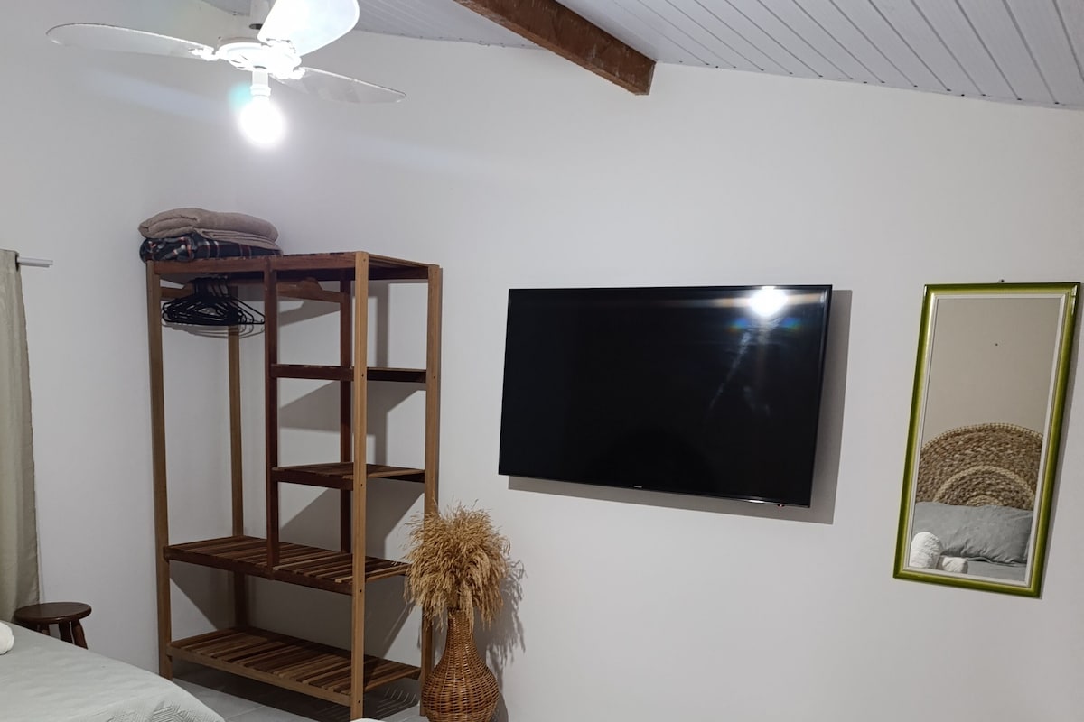 Ein Hotelzimmer mit zwei Betten, einem Fernseher, einem Spiegel und einem Deckenventilator.