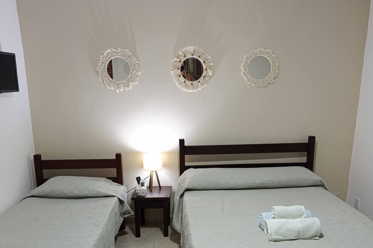Ein Zimmer mit zwei Betten, einem Nachttisch mit Lampe und dekorativen Spiegeln an der Wand.